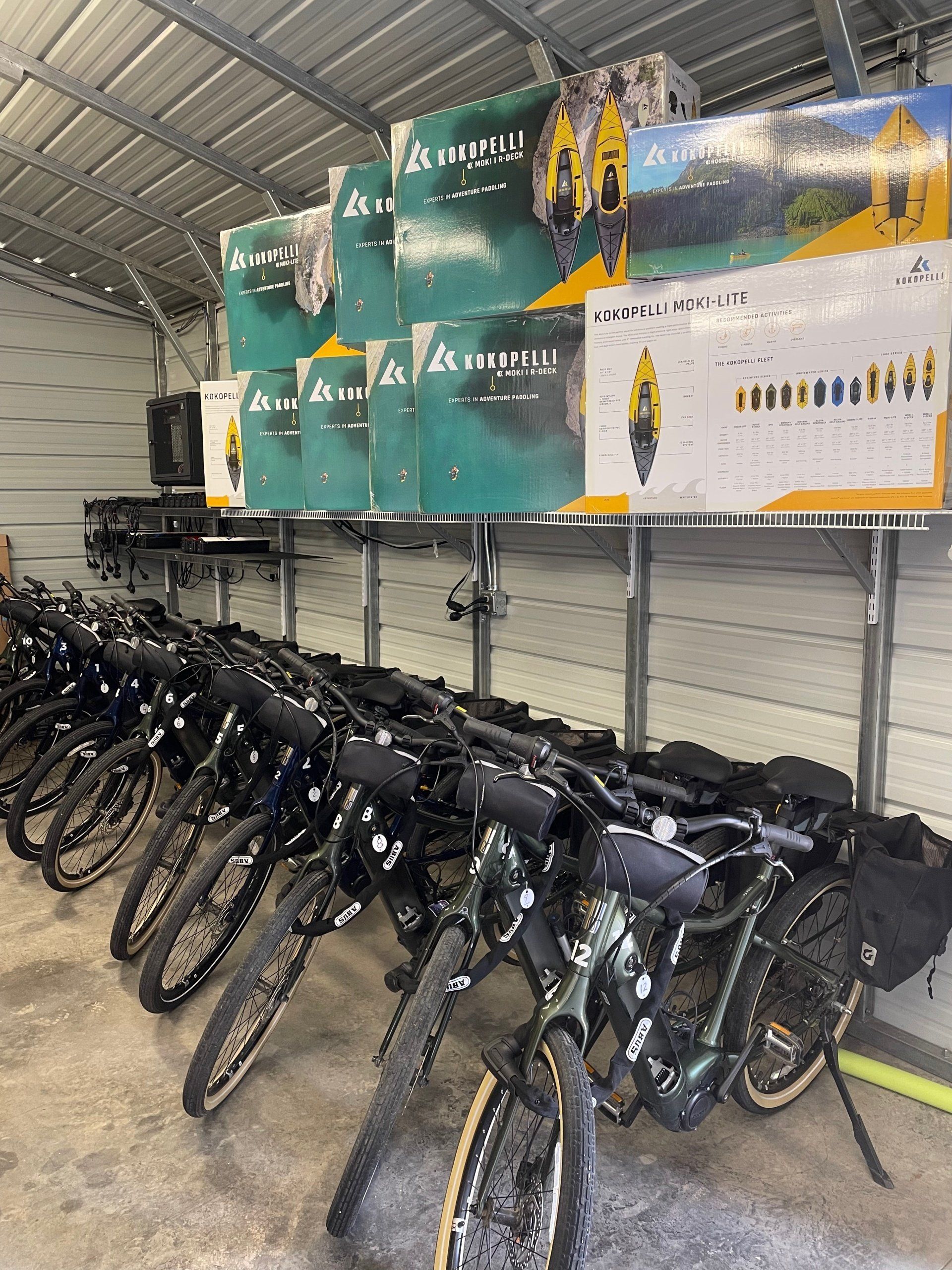 A row of bicycles are lined up in a warehouse.
