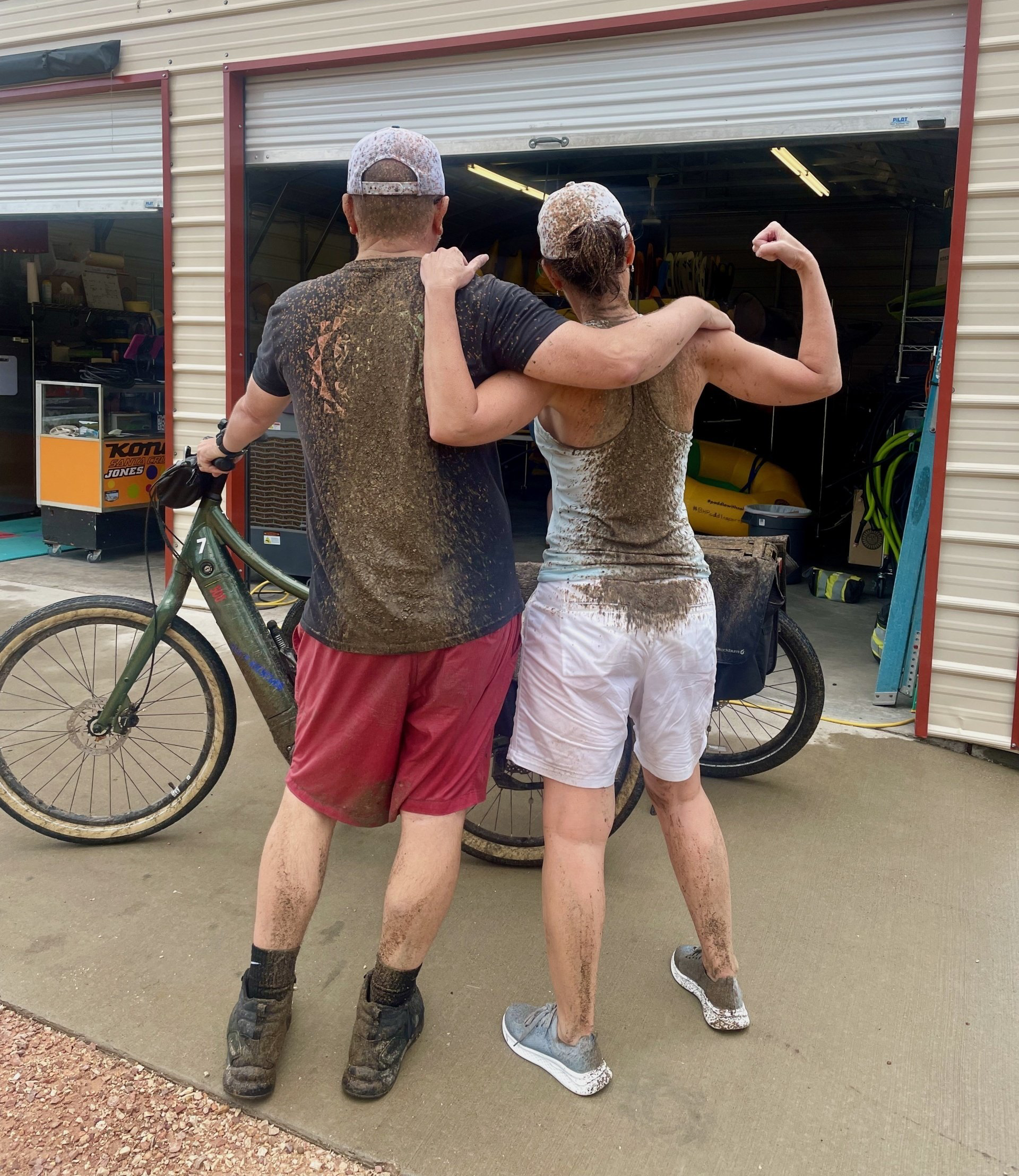 A man and a woman are standing next to a bicycle in front of a garage.