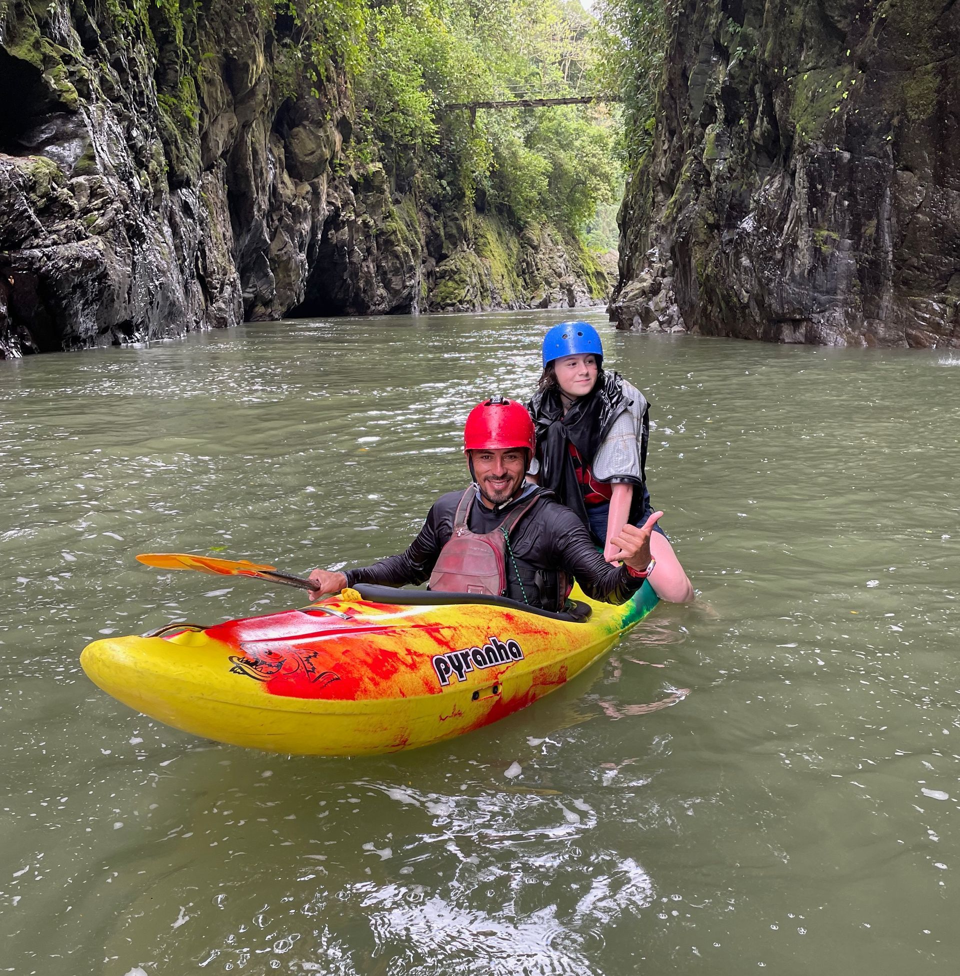 A man and a woman are riding a kayak down a river.