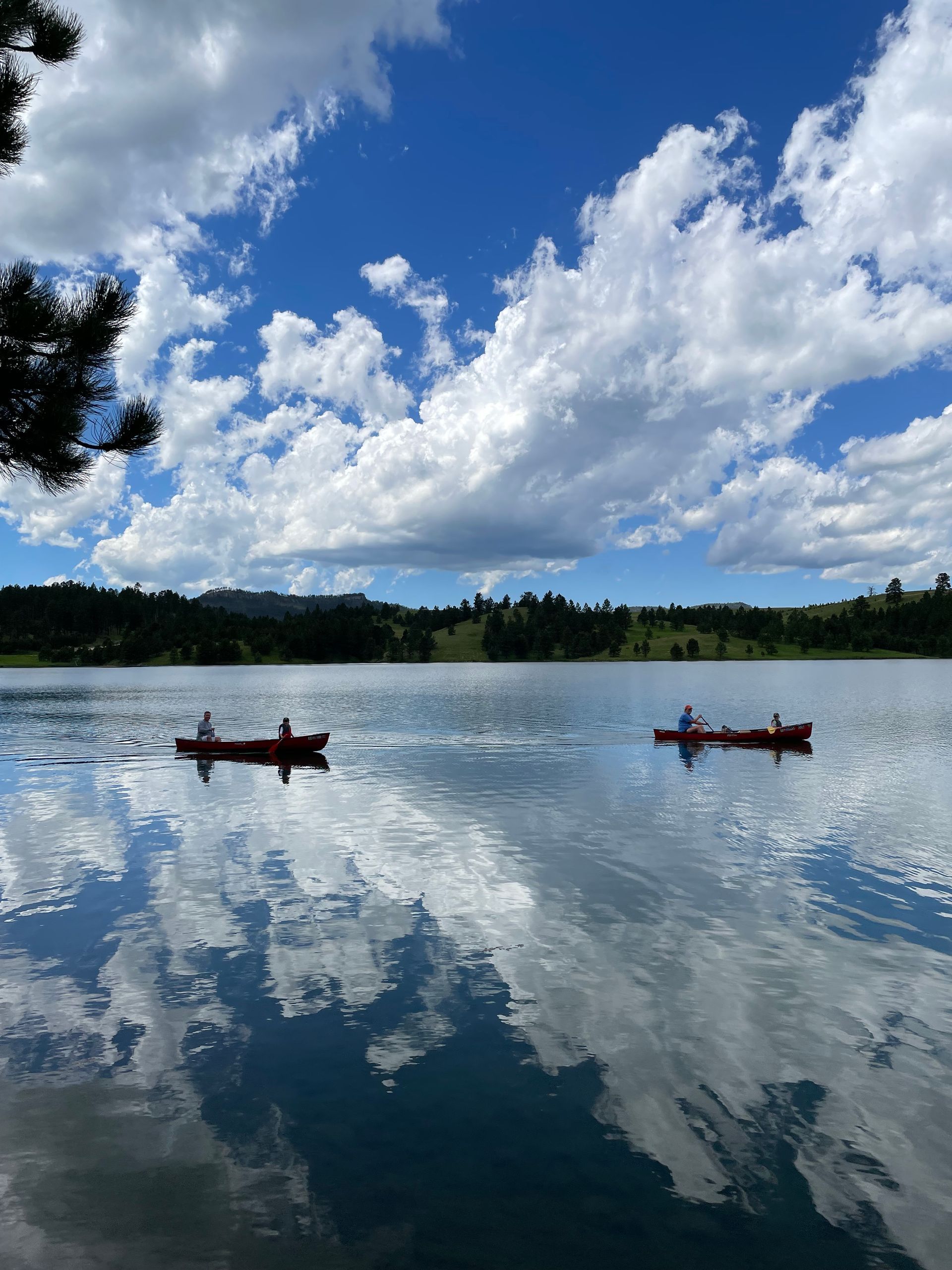 Two people are kayaking on a lake on a sunny day