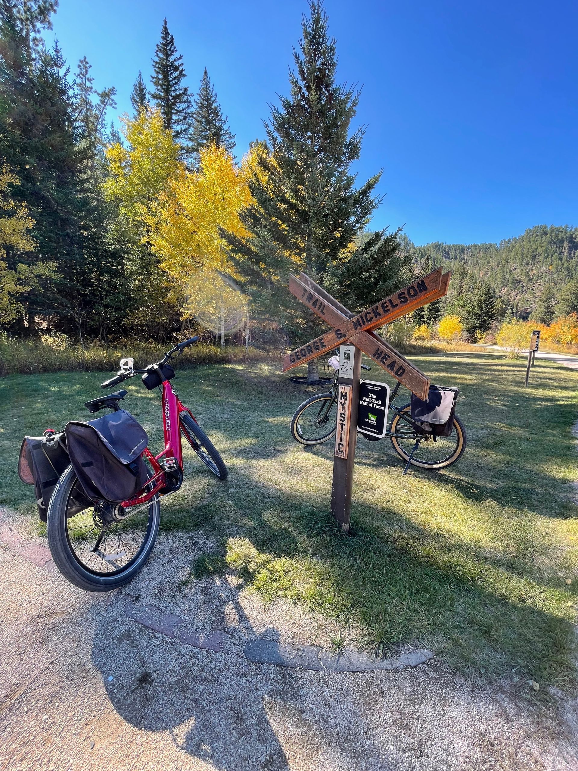 A bicycle is parked next to a sign on a dirt road.