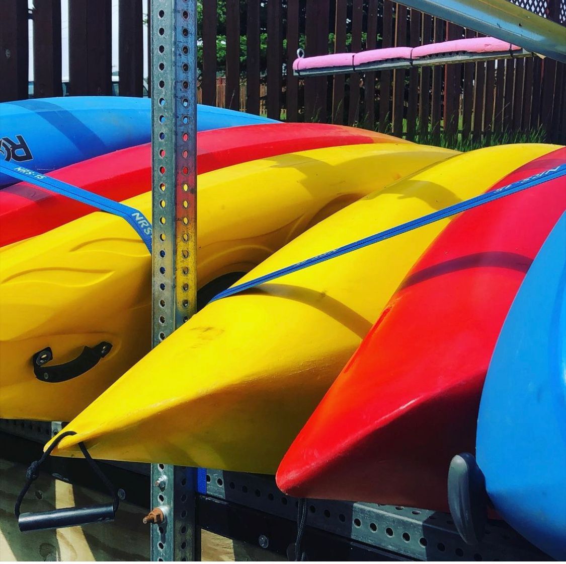 A bunch of colorful kayaks are lined up on a rack