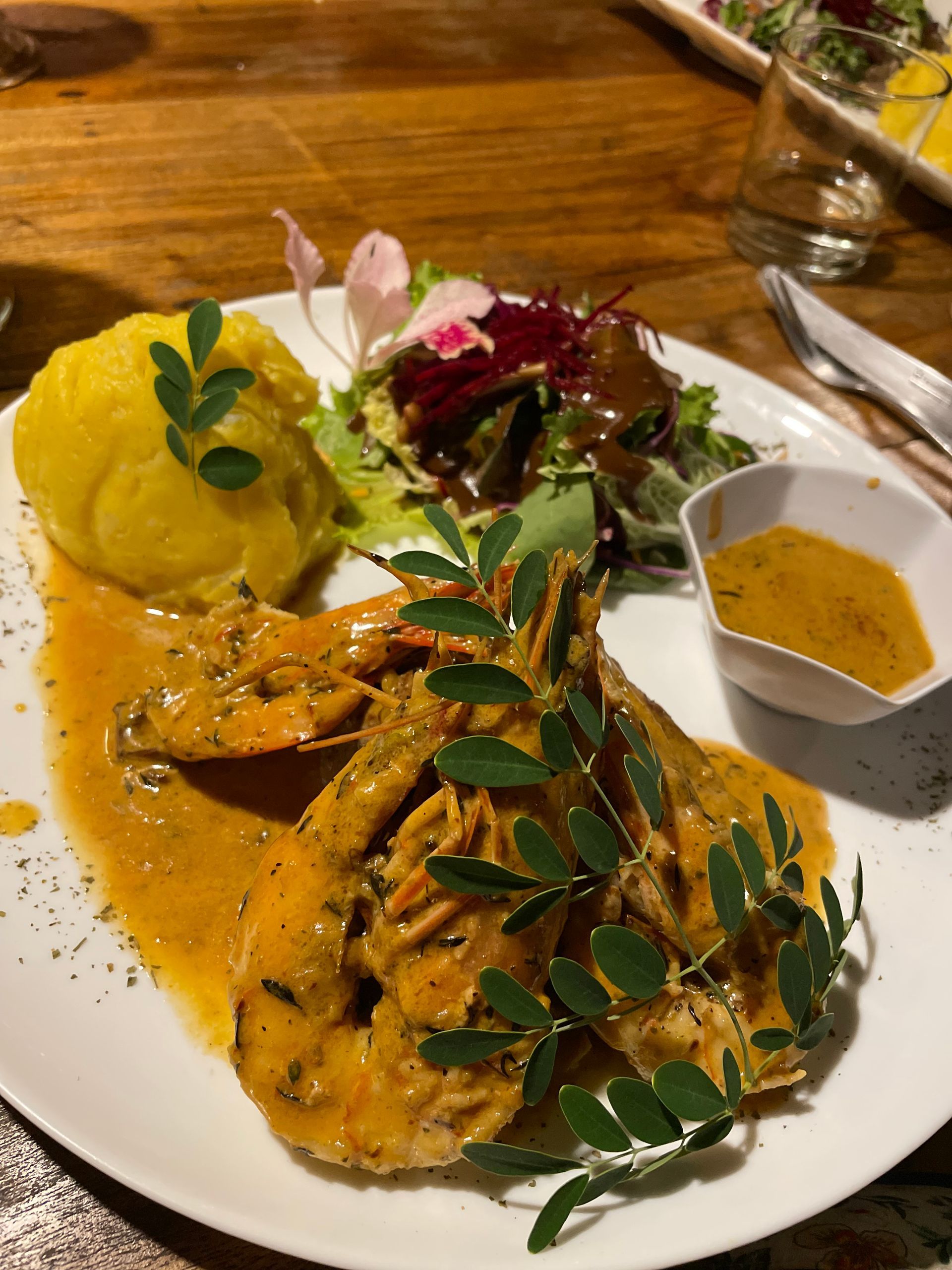 A plate of food with shrimp , mashed potatoes , and sauce on a table.