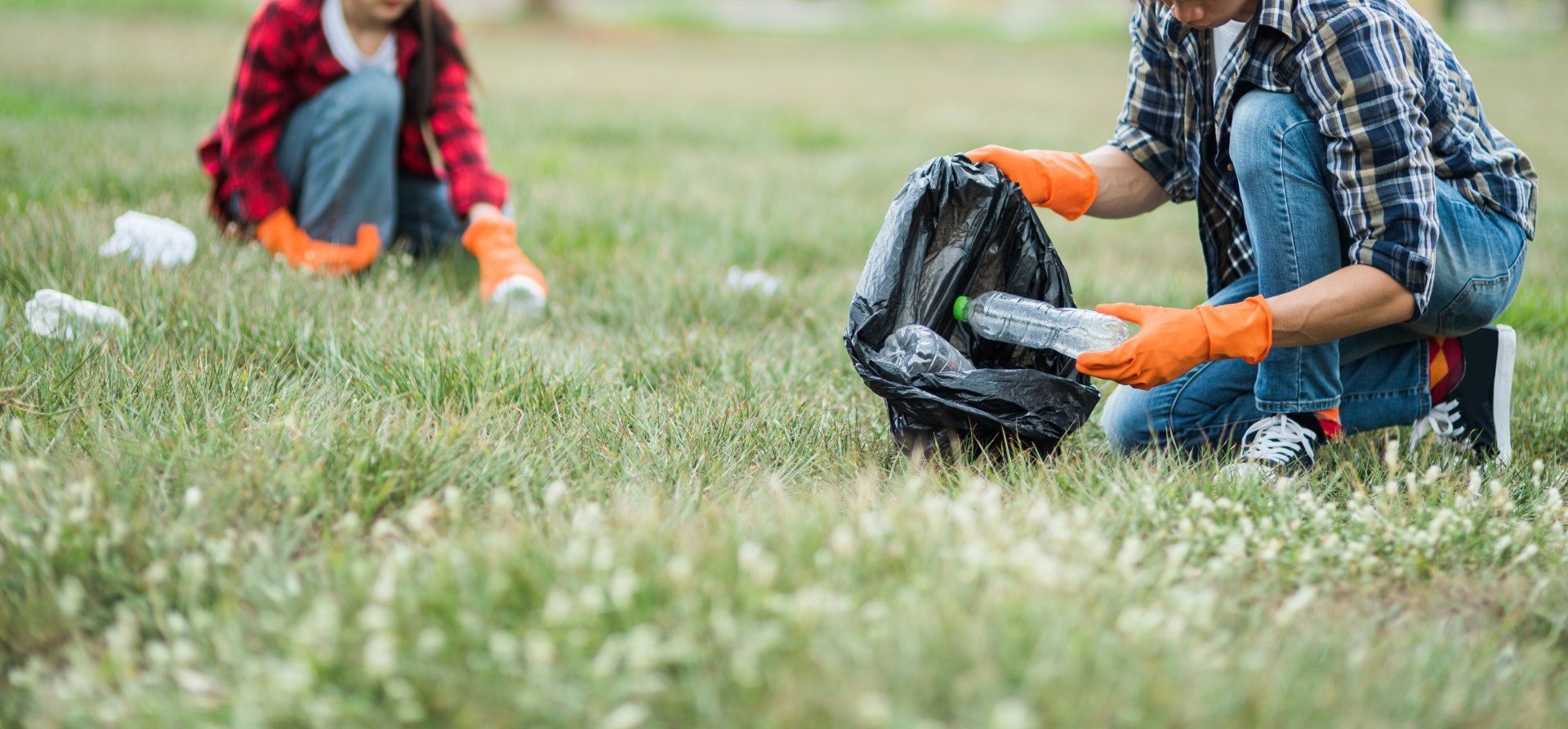 Voluntarios recolectando basura de plástico en el pasto compromiso ambiental