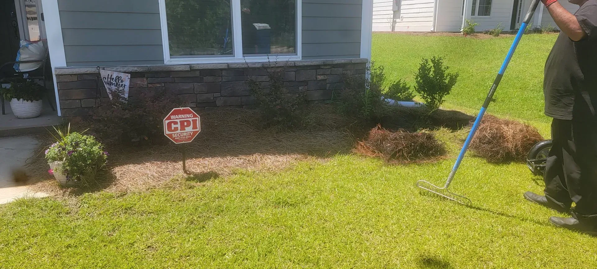 Person raking grass near a house with a window and a CPI sign.