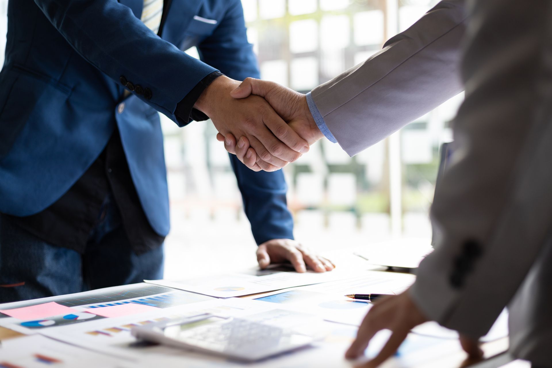 Two business people are shaking hands over a table.