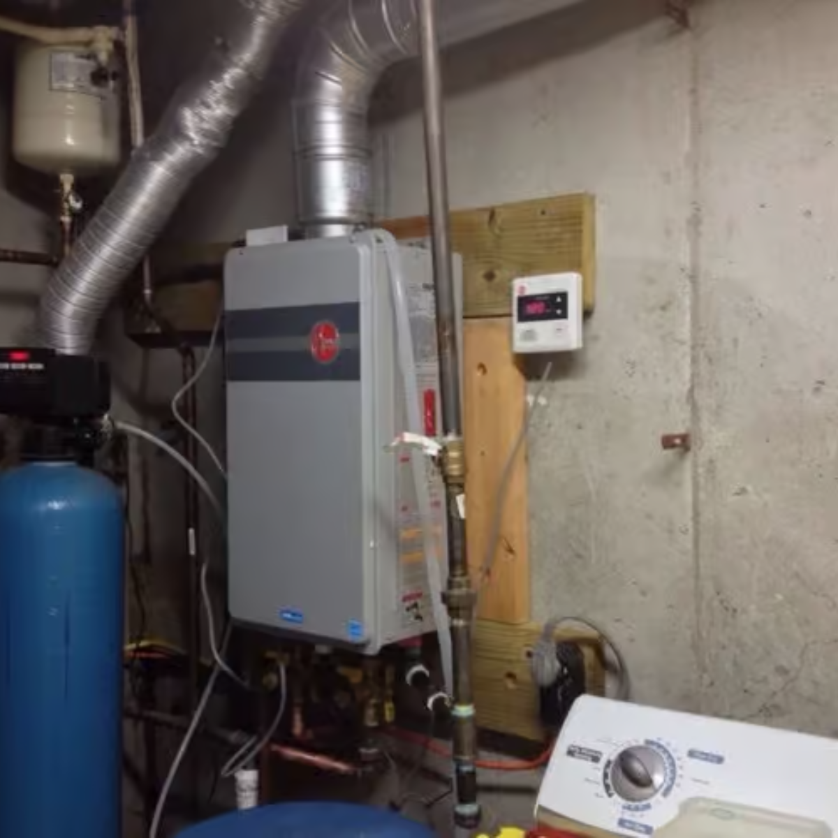 Tankless water heater and water softener in a basement utility area.