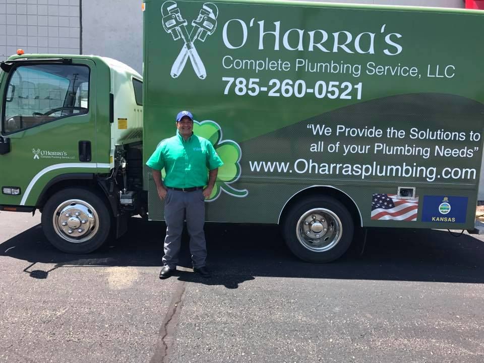Man stands by a green O'Harra's plumbing truck; company logo and phone number are visible.