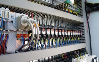 A close up of a electrical panel with a lot of wires coming out of it.