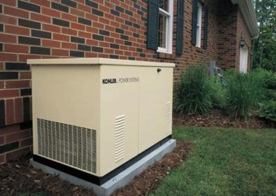 A generator is sitting on the side of a brick house.