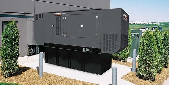 A large black generator is sitting outside of a building.