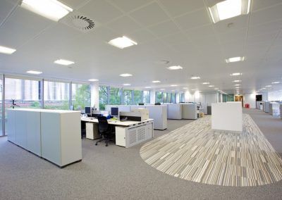 A large empty office with a lot of desks and chairs.