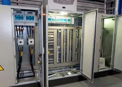 A row of electrical cabinets with their doors open in a room.