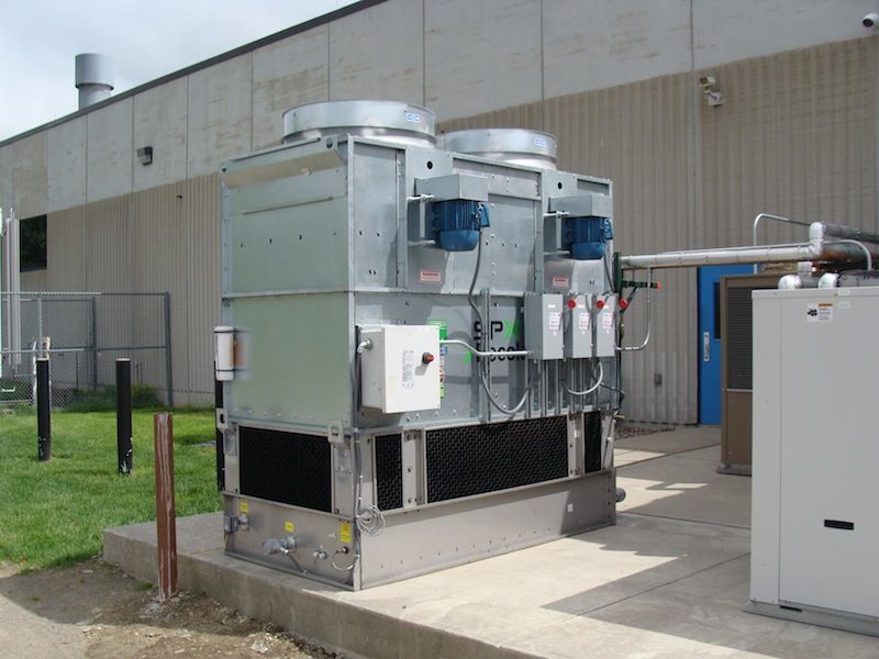 A large cooling tower is outside of a building