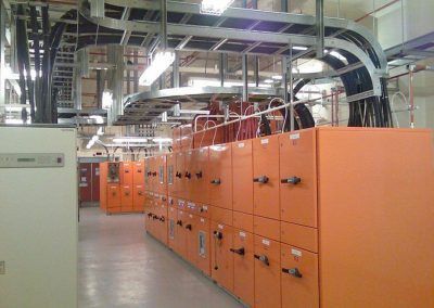 A row of orange cabinets in a room with lots of wires hanging from the ceiling.