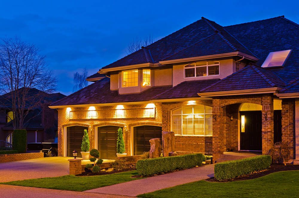 A large house is lit up at night in a residential area.