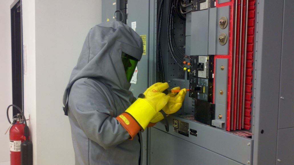 A man in a protective suit is working on an electrical box.