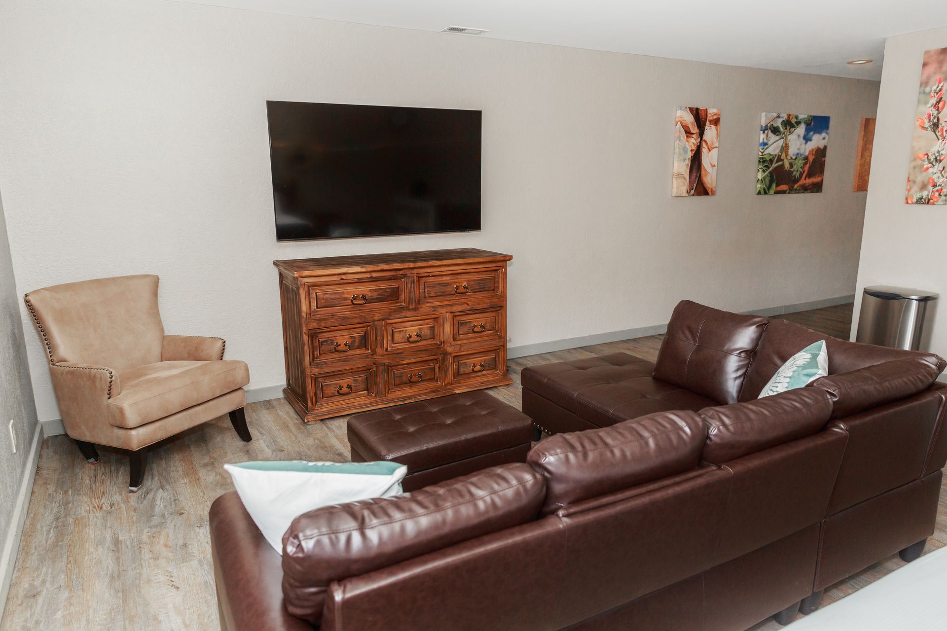 A living room with a couch , chair , ottoman and television.