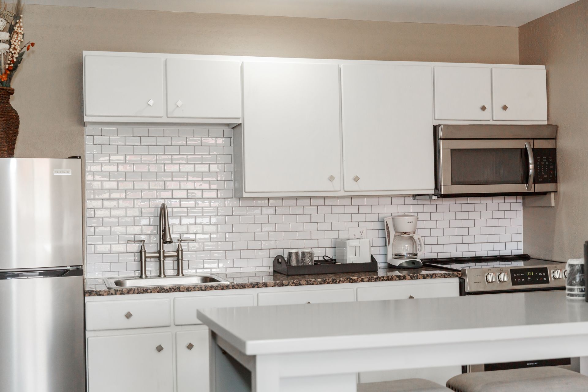 A kitchen with white cabinets and stainless steel appliances