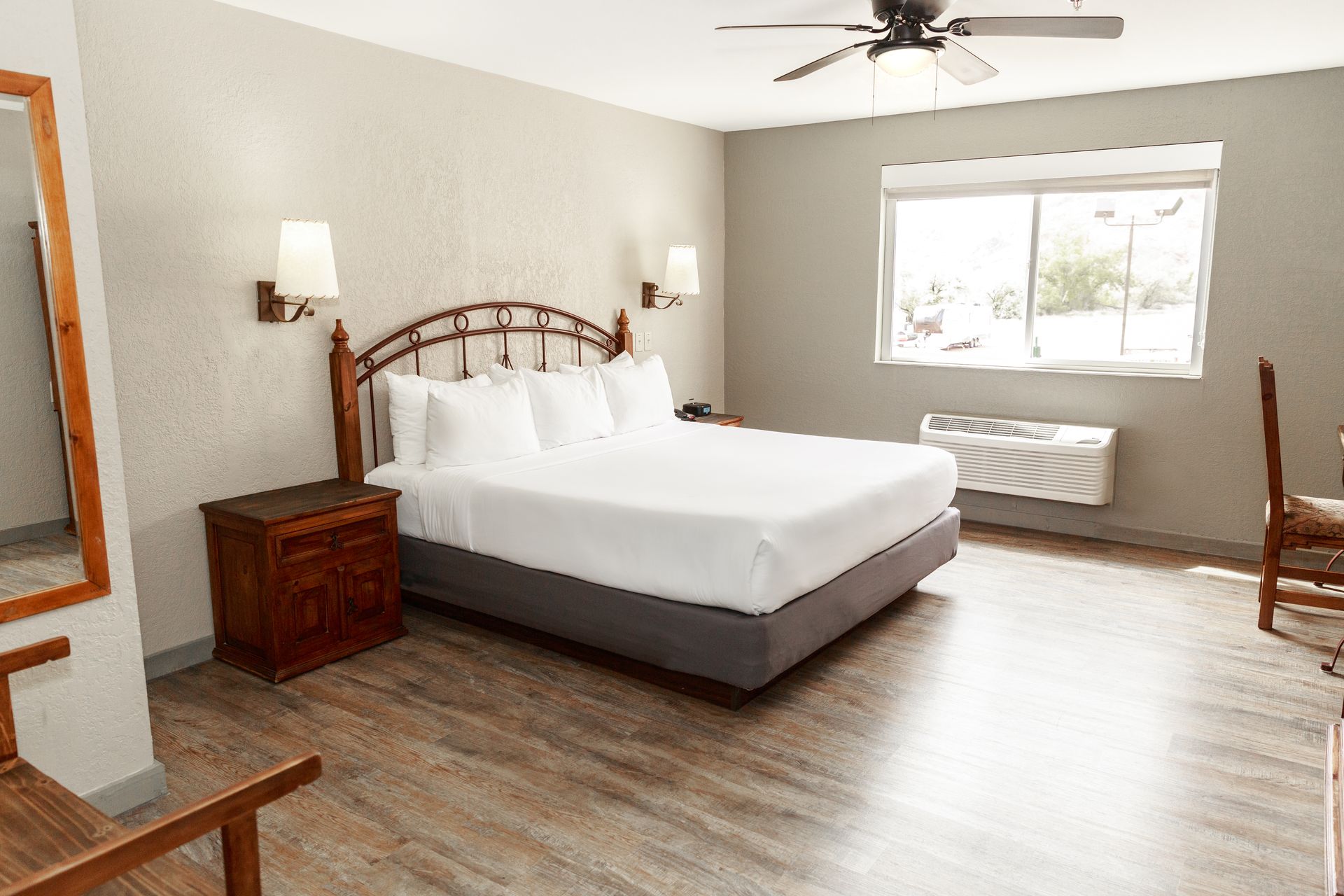 A hotel room with a king size bed and a ceiling fan.