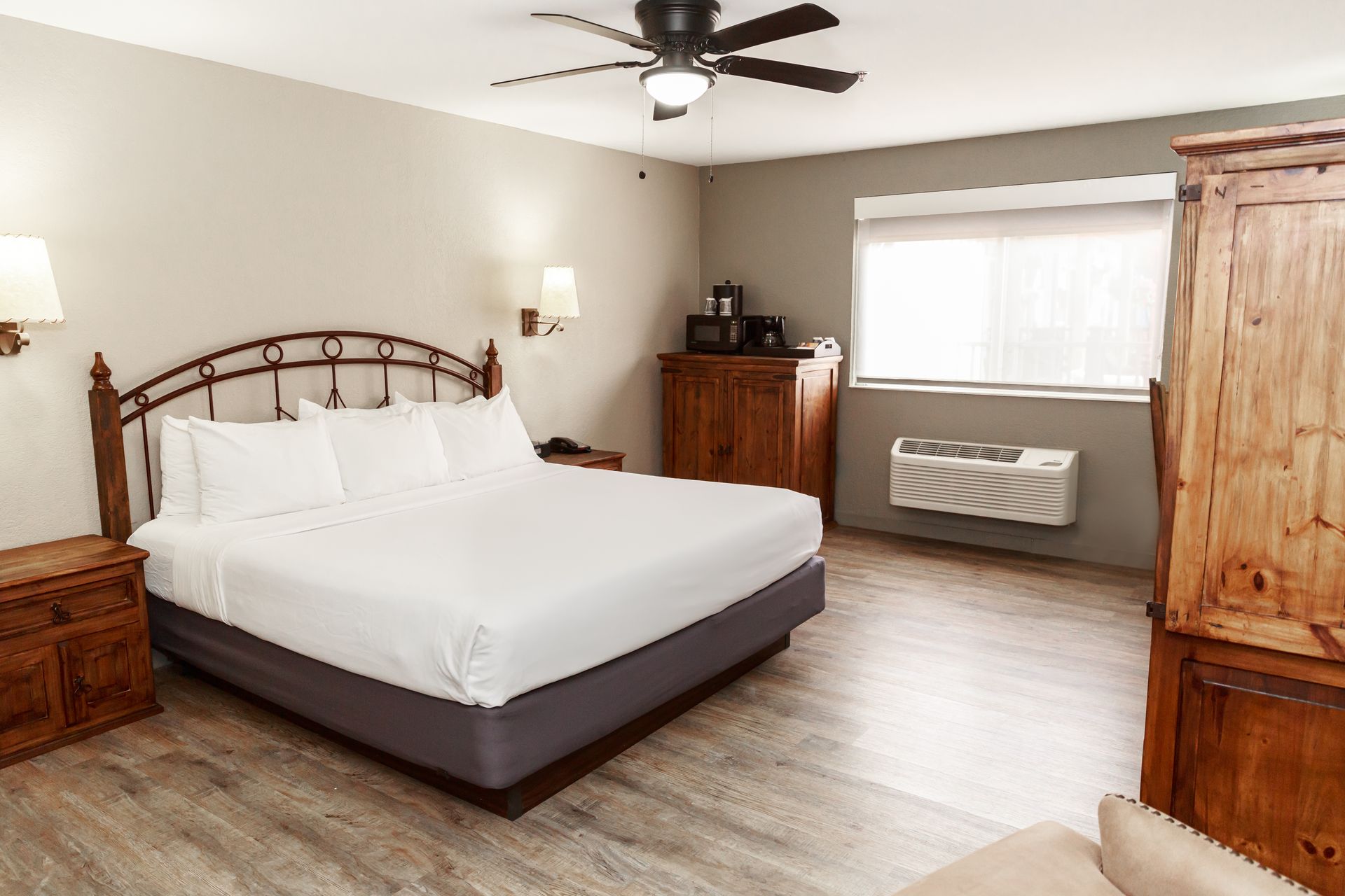 A hotel room with a king size bed and a ceiling fan.