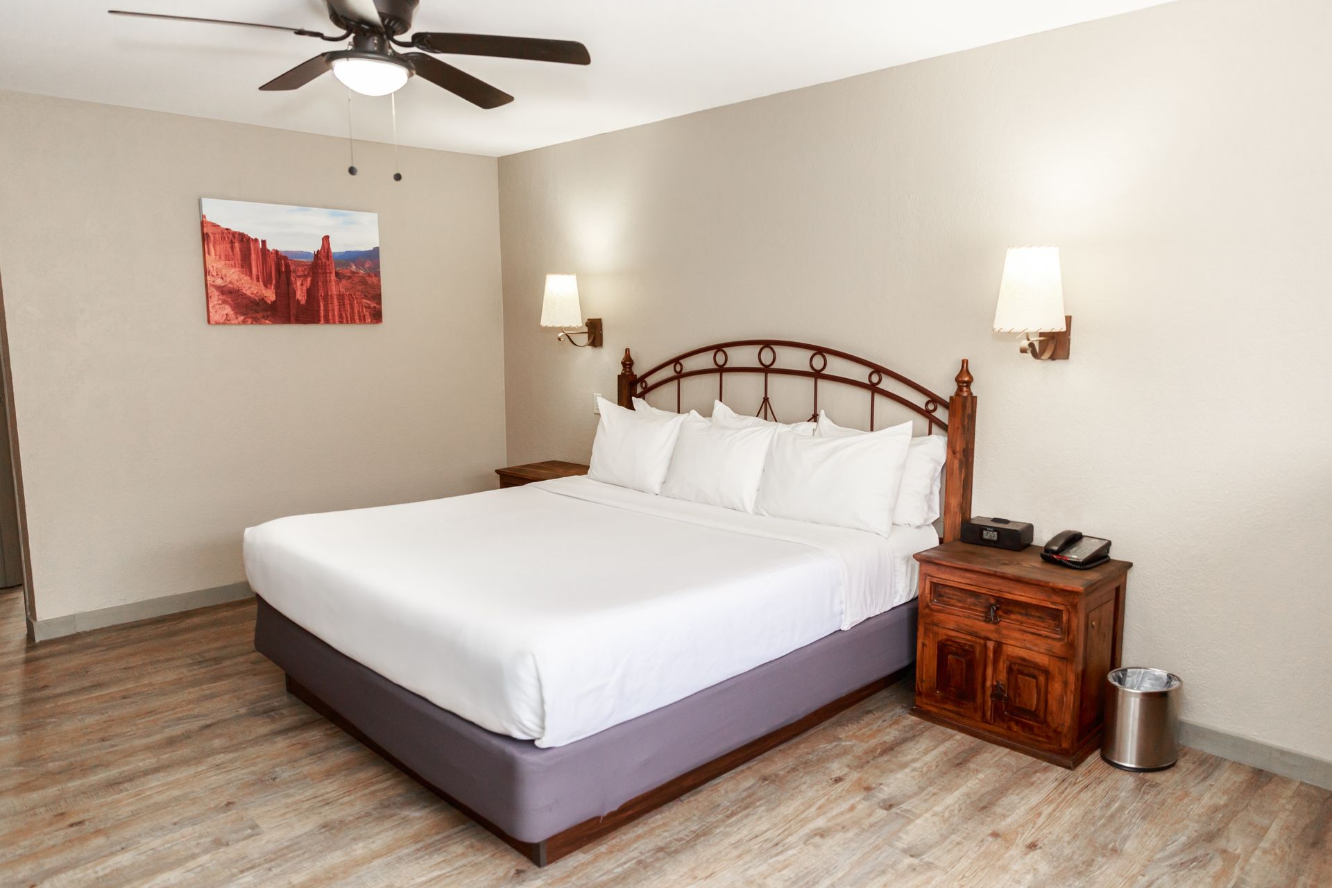 A hotel room with a king size bed and a ceiling fan.