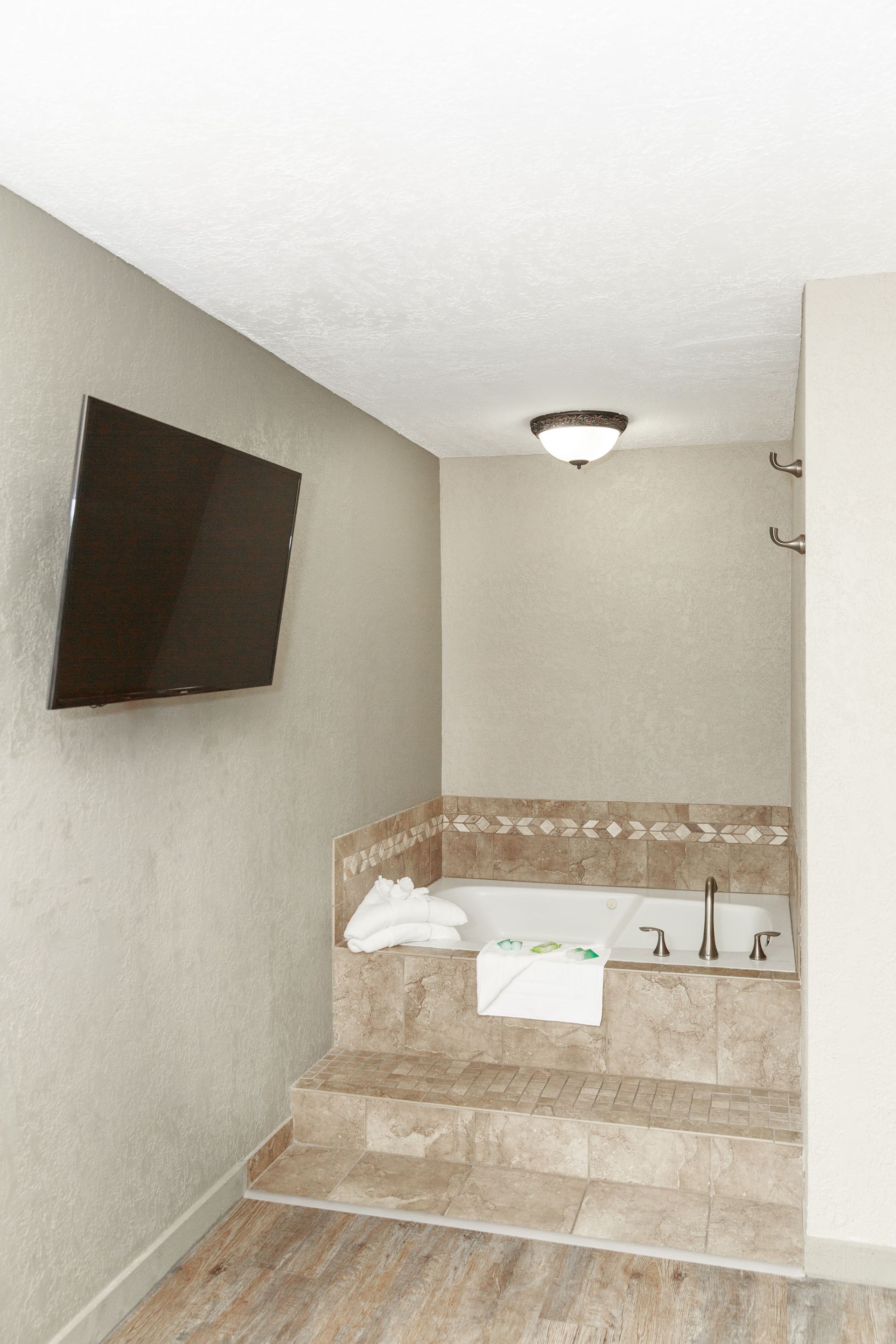 A bathroom with a jacuzzi tub and a flat screen tv.