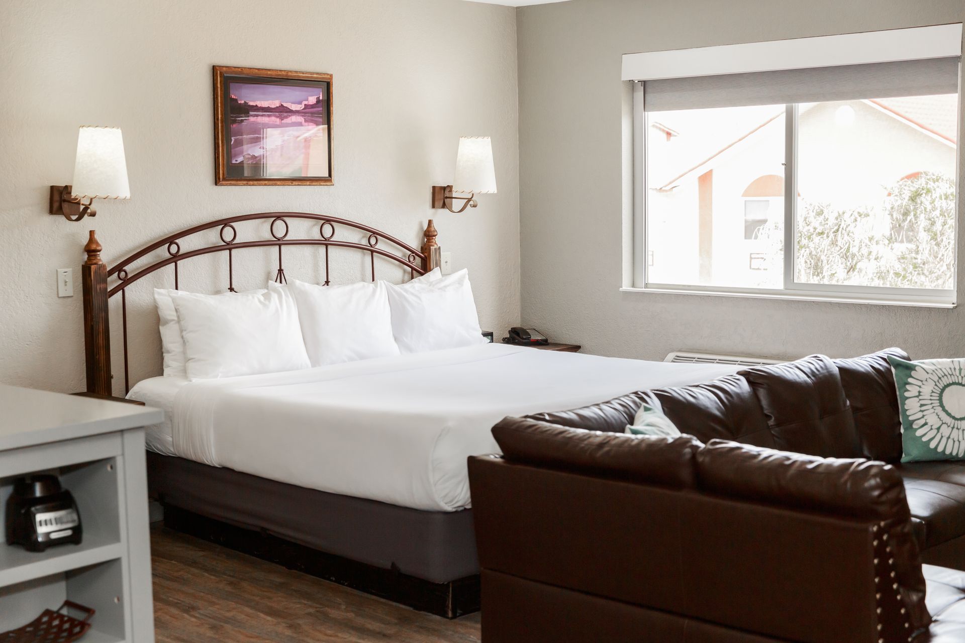 A hotel room with a king size bed , couch , and window.