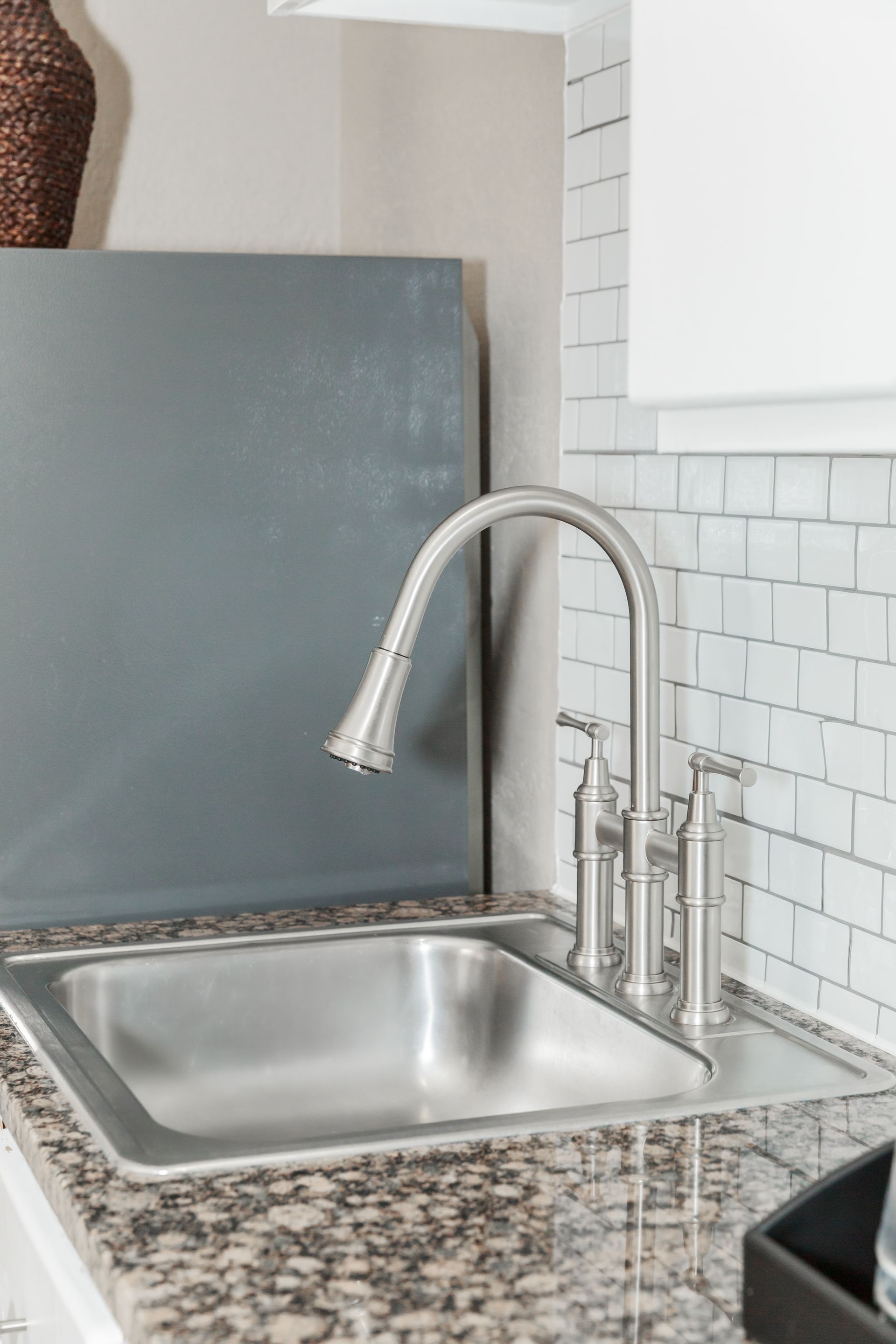 A kitchen sink with a faucet on a granite counter top.