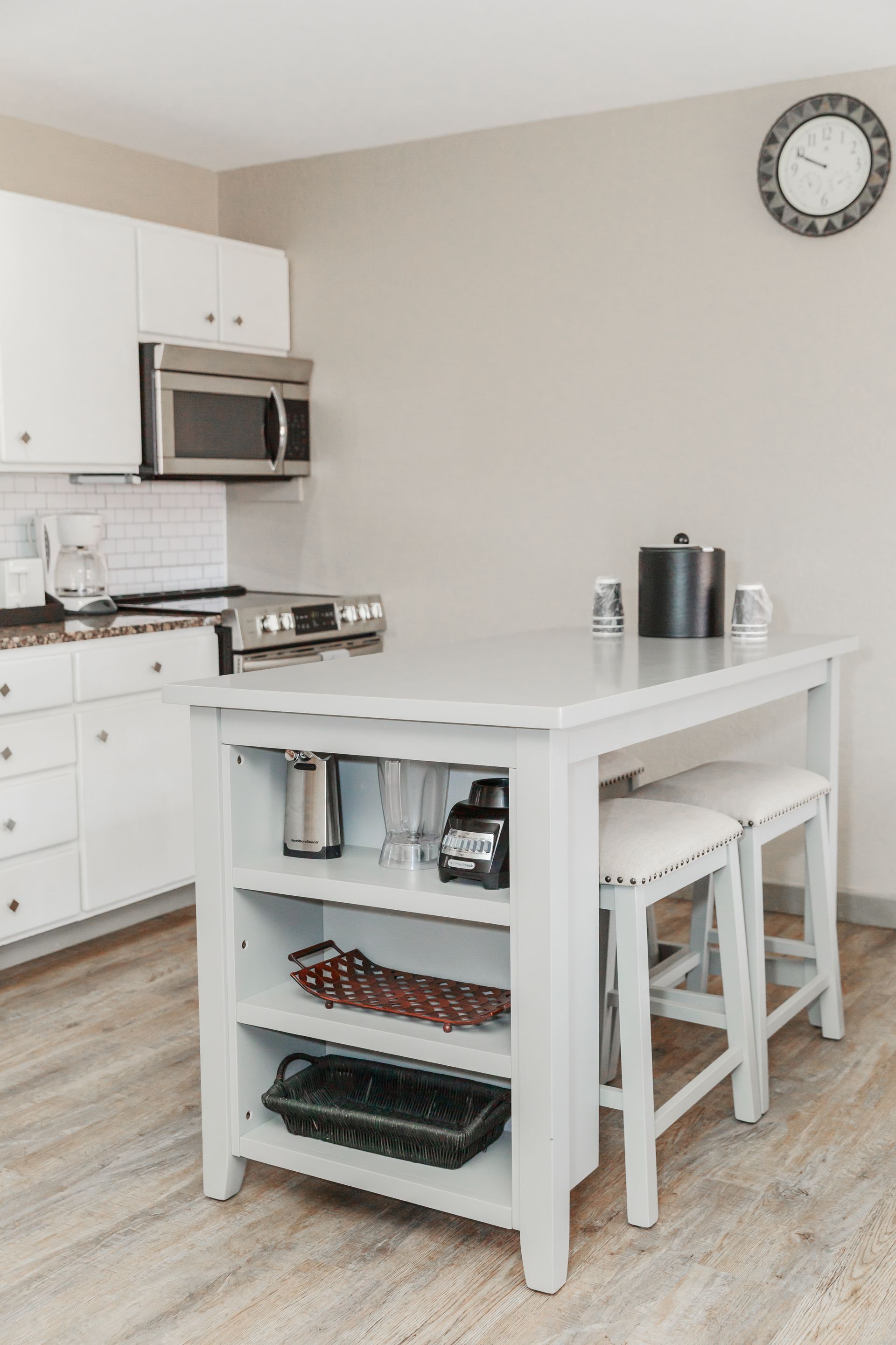 A kitchen with a table and stools and a clock on the wall.