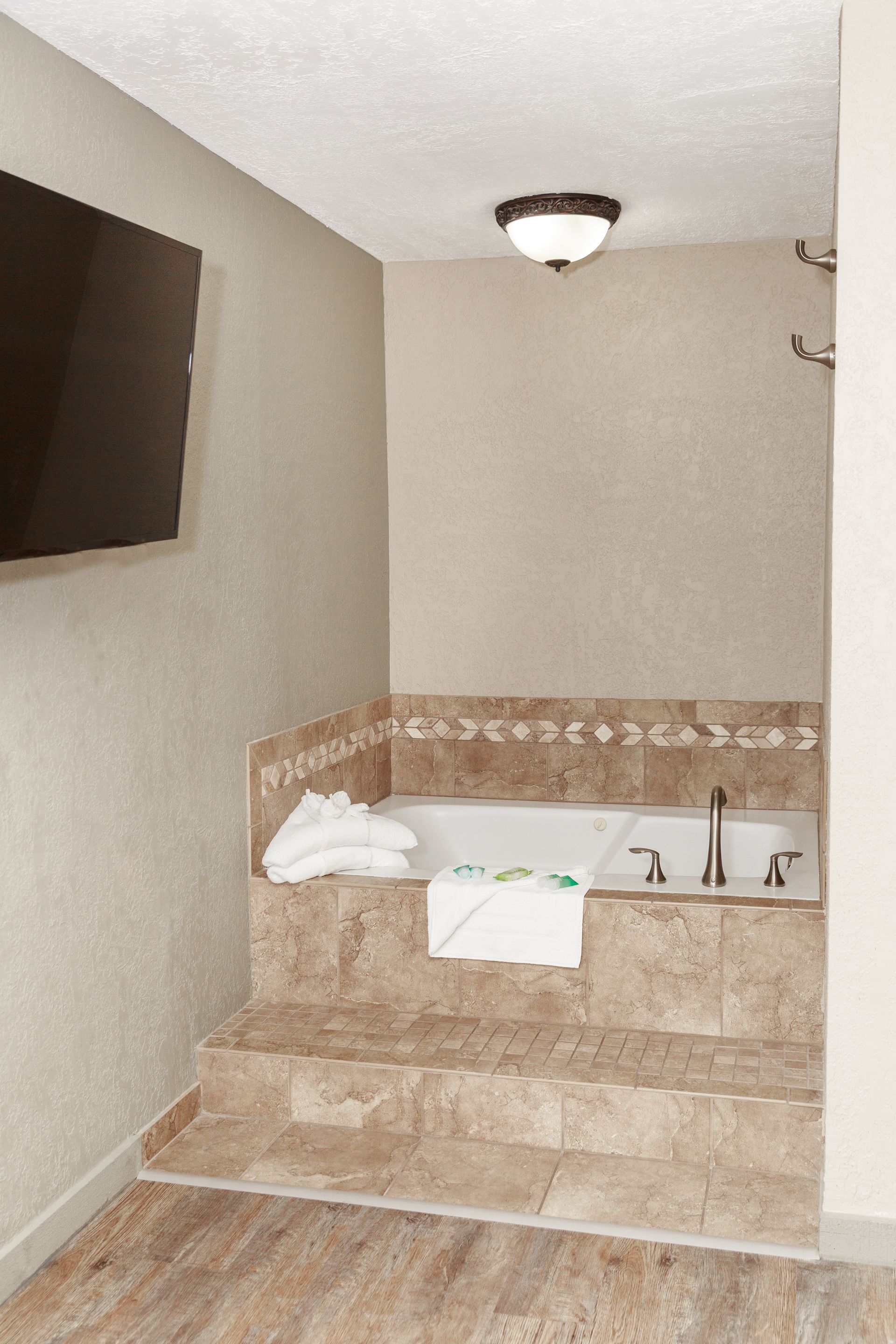 A bathroom with a jacuzzi tub and a flat screen tv.