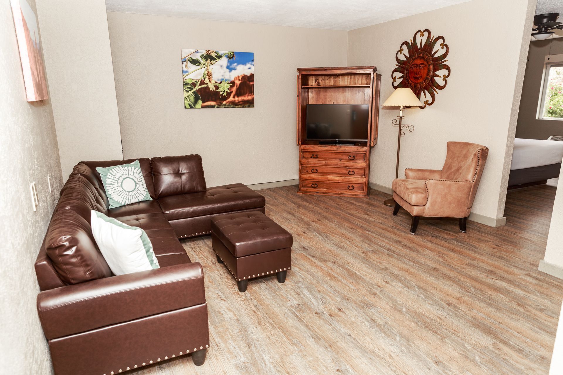 A living room with a couch , chair , ottoman and television.