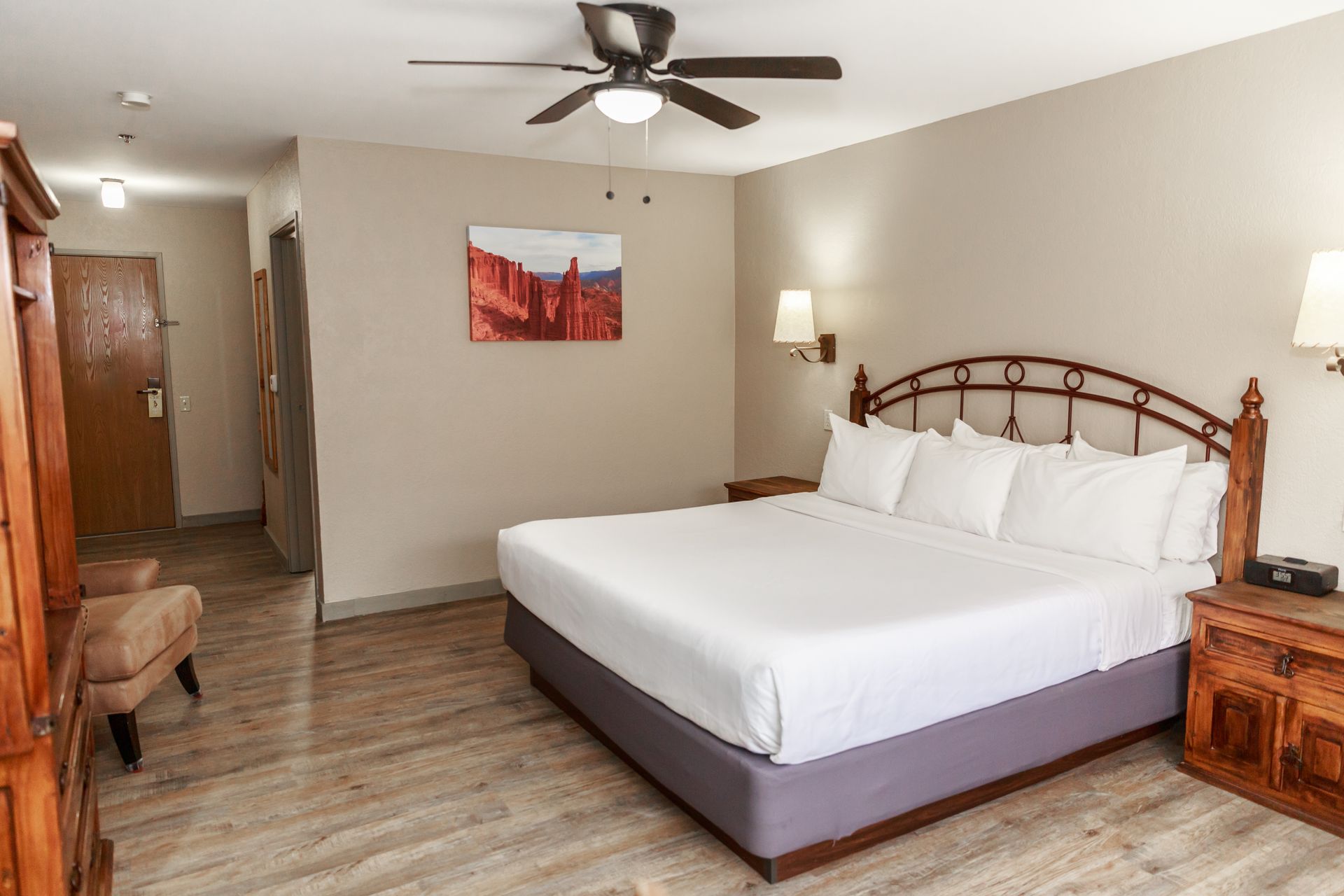 A hotel room with a king size bed and a ceiling fan.