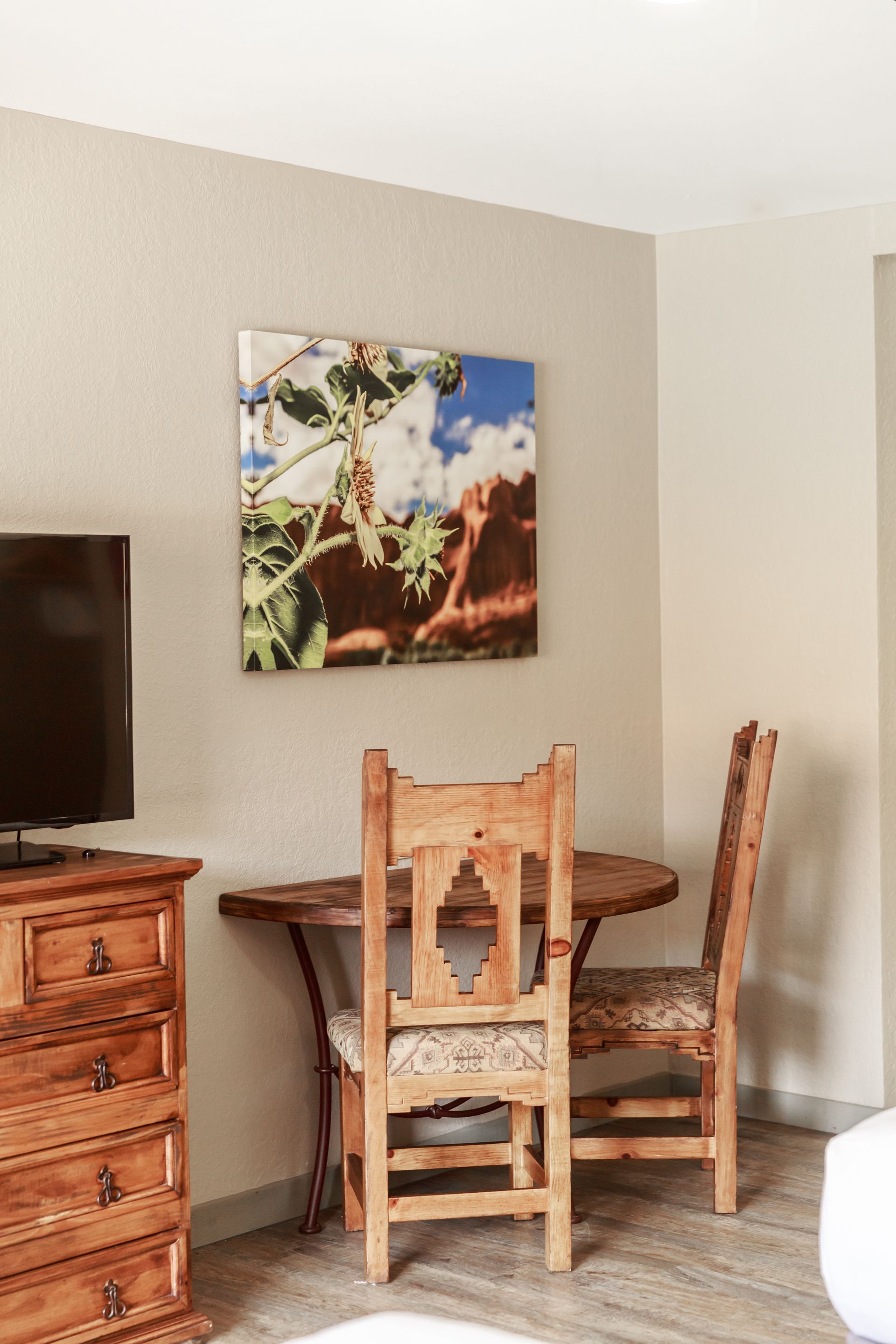 A hotel room with a table , chairs , dresser and television.