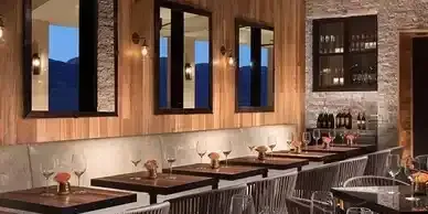 A restaurant with tables and chairs and glasses of wine.