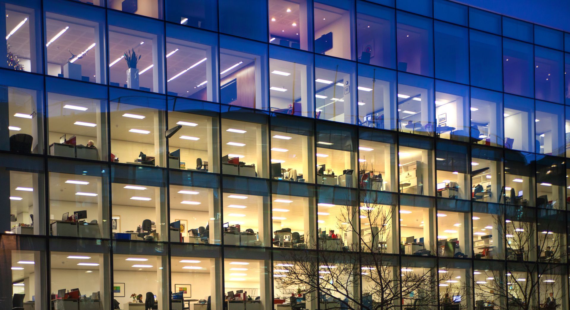 A large office building with lots of windows is lit up at night.