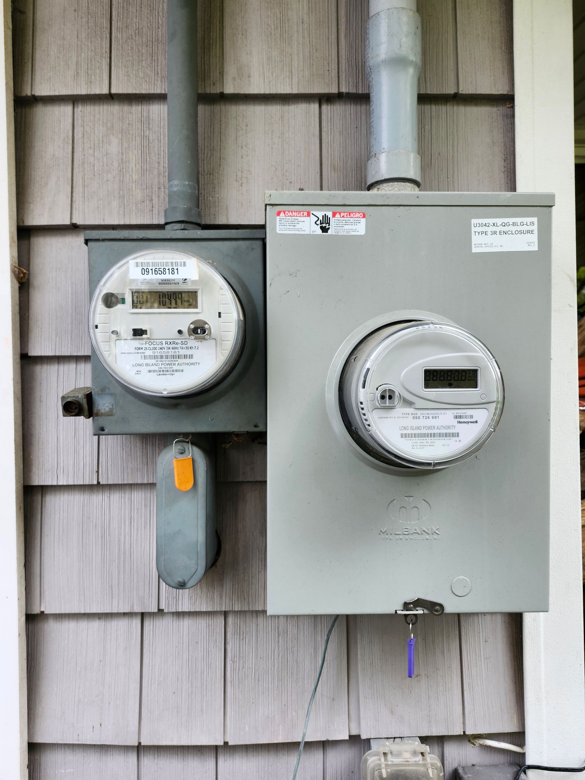 There are two electrical meters on the side of a building.