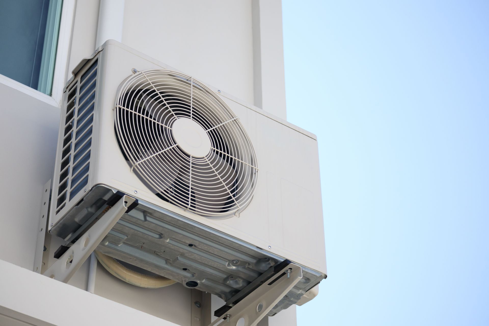 A white air conditioner is mounted on the side of a building.