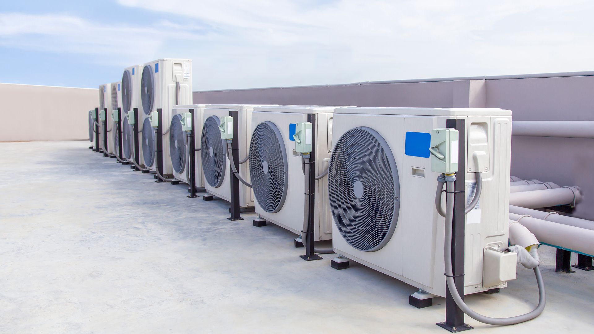 A row of air conditioners are lined up on the roof of a building.