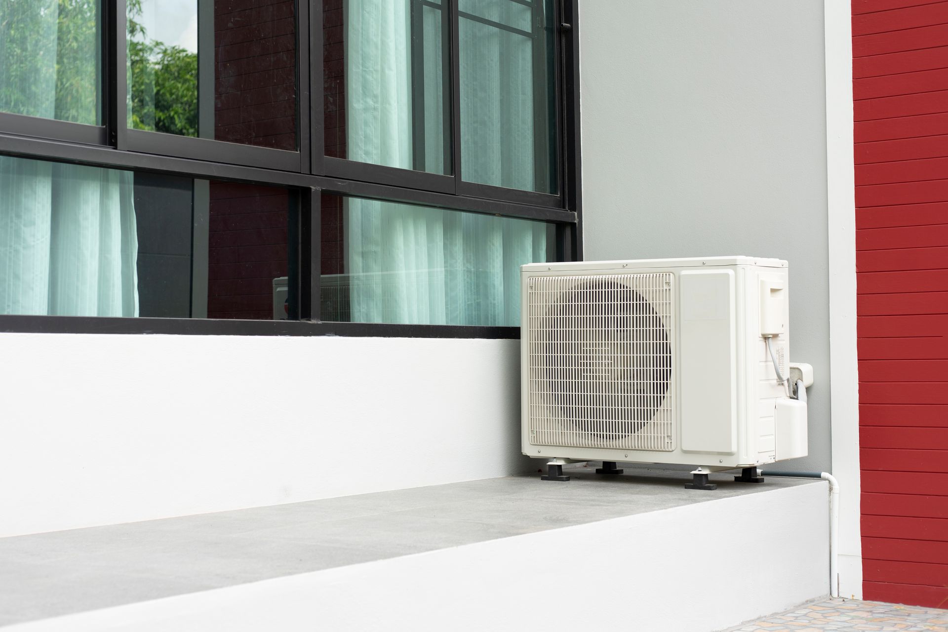 A white air conditioner is sitting on a window sill next to a window.