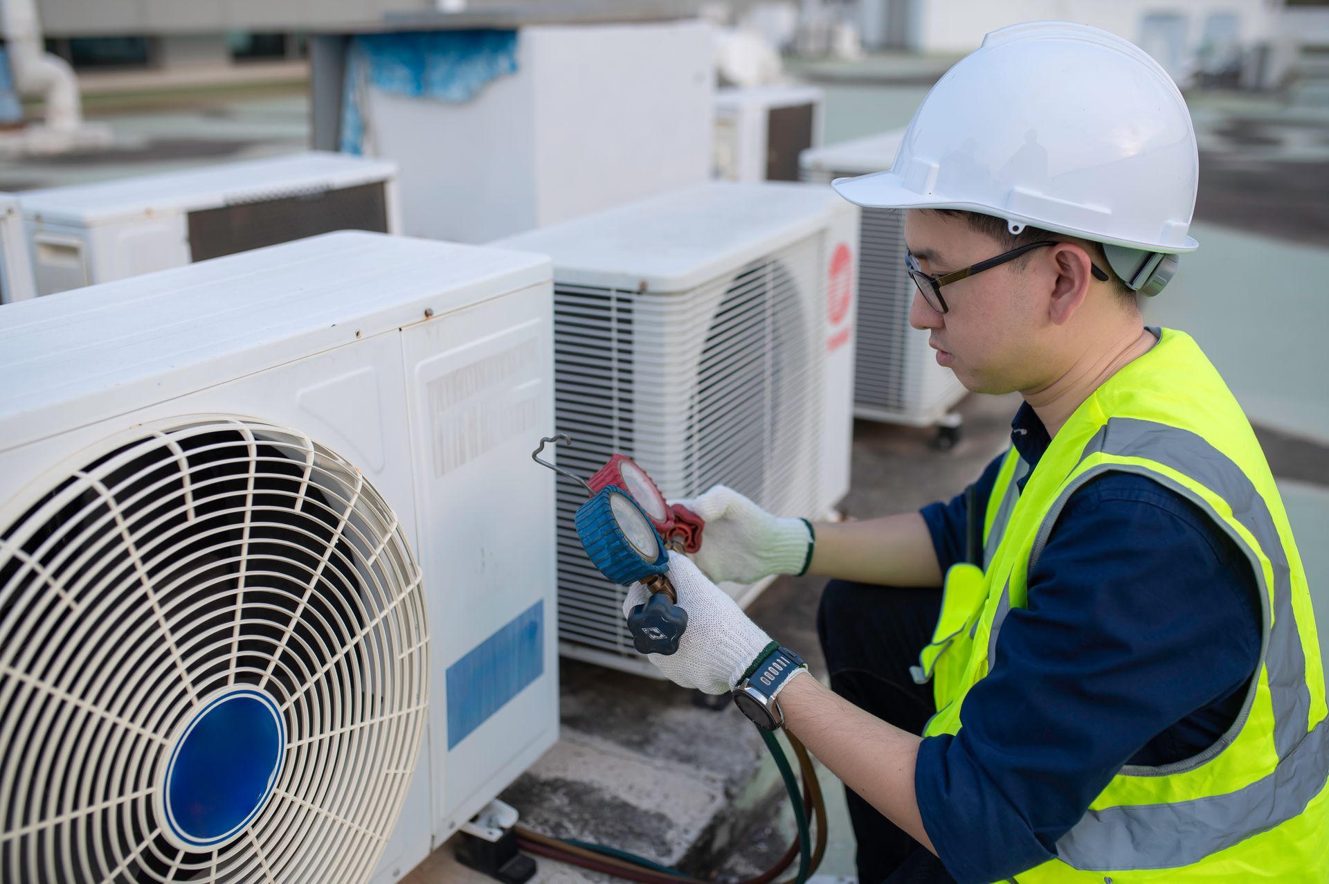 A man is working on an air conditioner on the roof of a building.