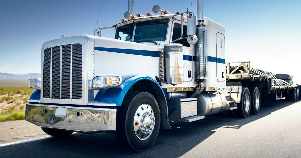 A white and blue semi truck is parked on the side of the road.