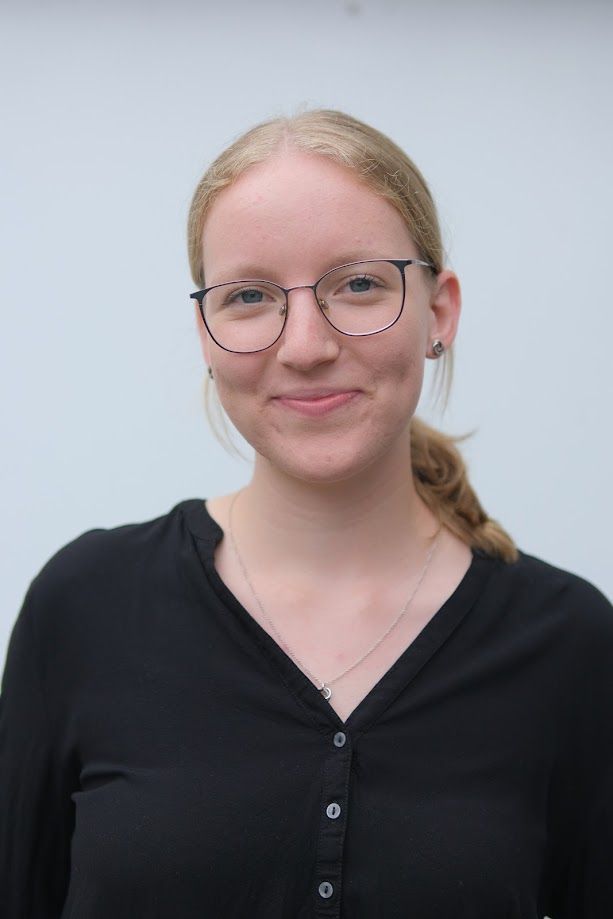Eine Frau mit Brille und schwarzem Hemd lächelt in die Kamera.