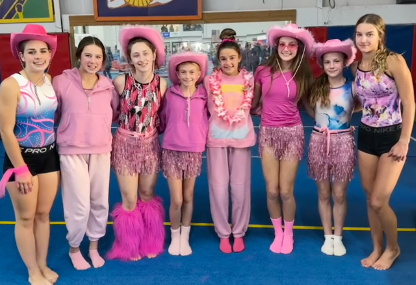 A group of girls wearing pink outfits and cowboy hats are posing for a picture.