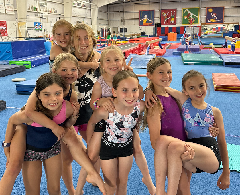 A group of young girls are posing for a picture in a gym.