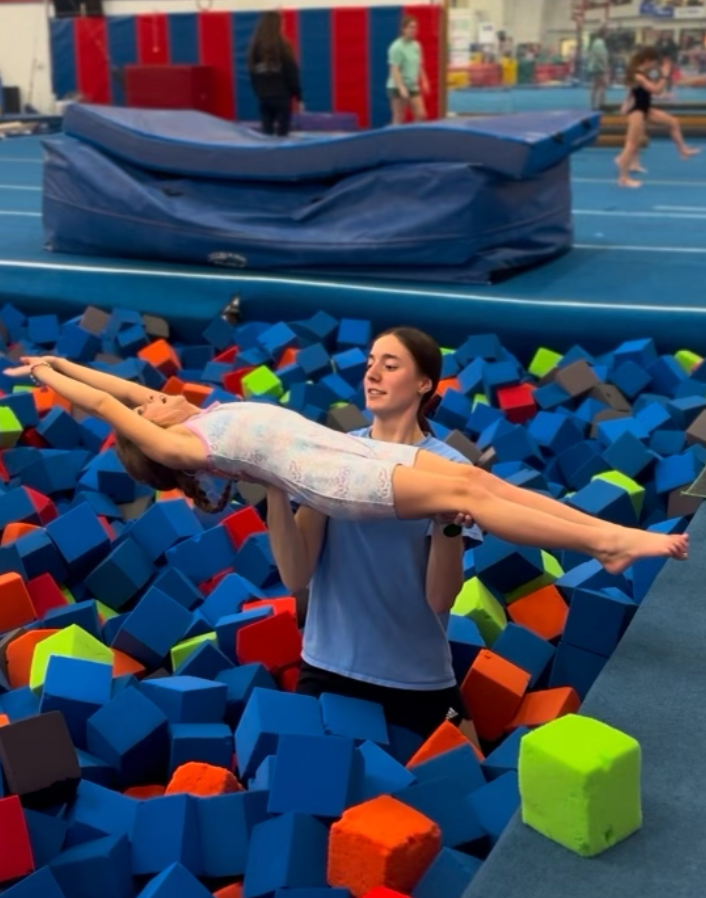 A woman is carrying a child in a pool of foam cubes.