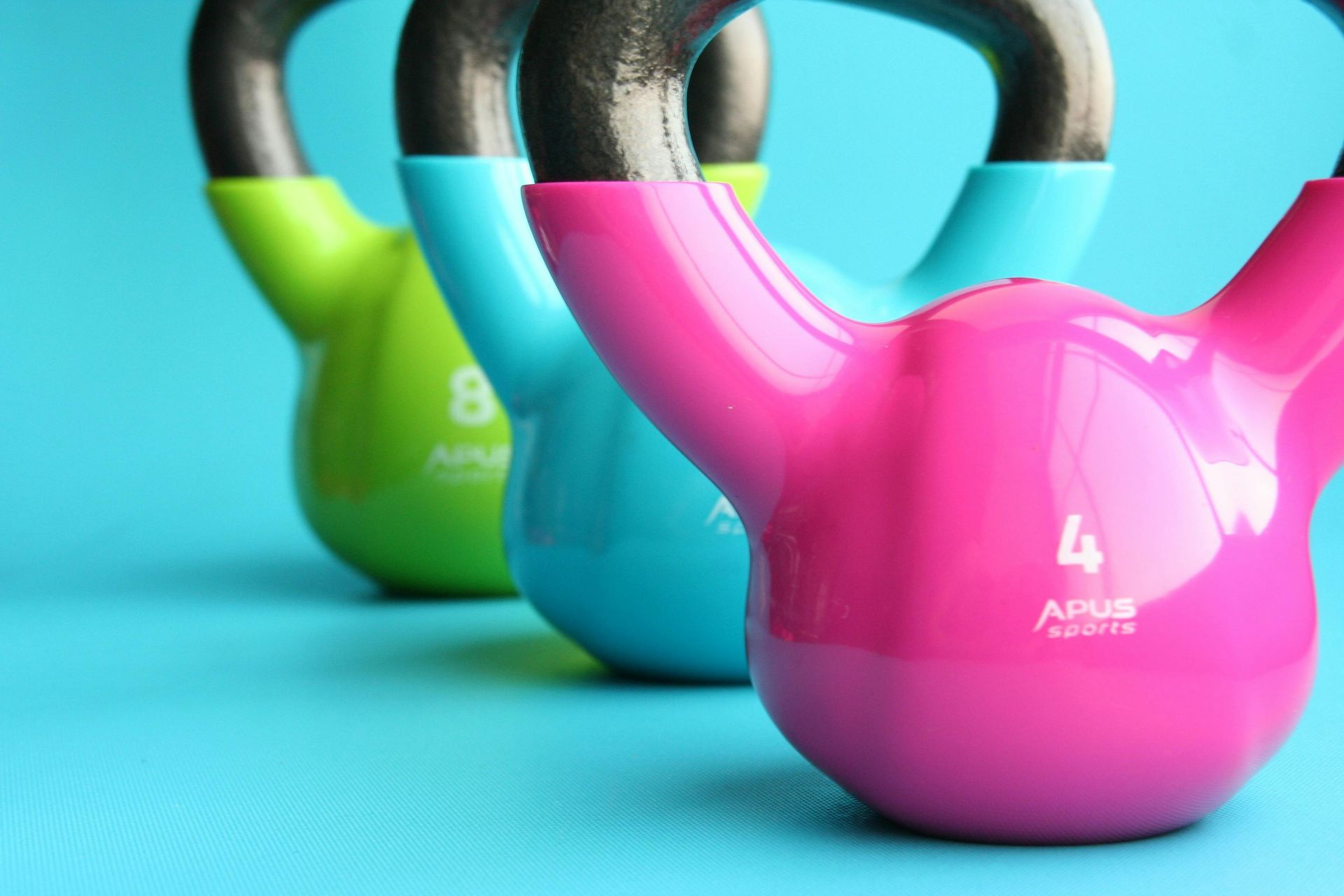 Three colorful kettlebells are lined up in a row on a blue background.