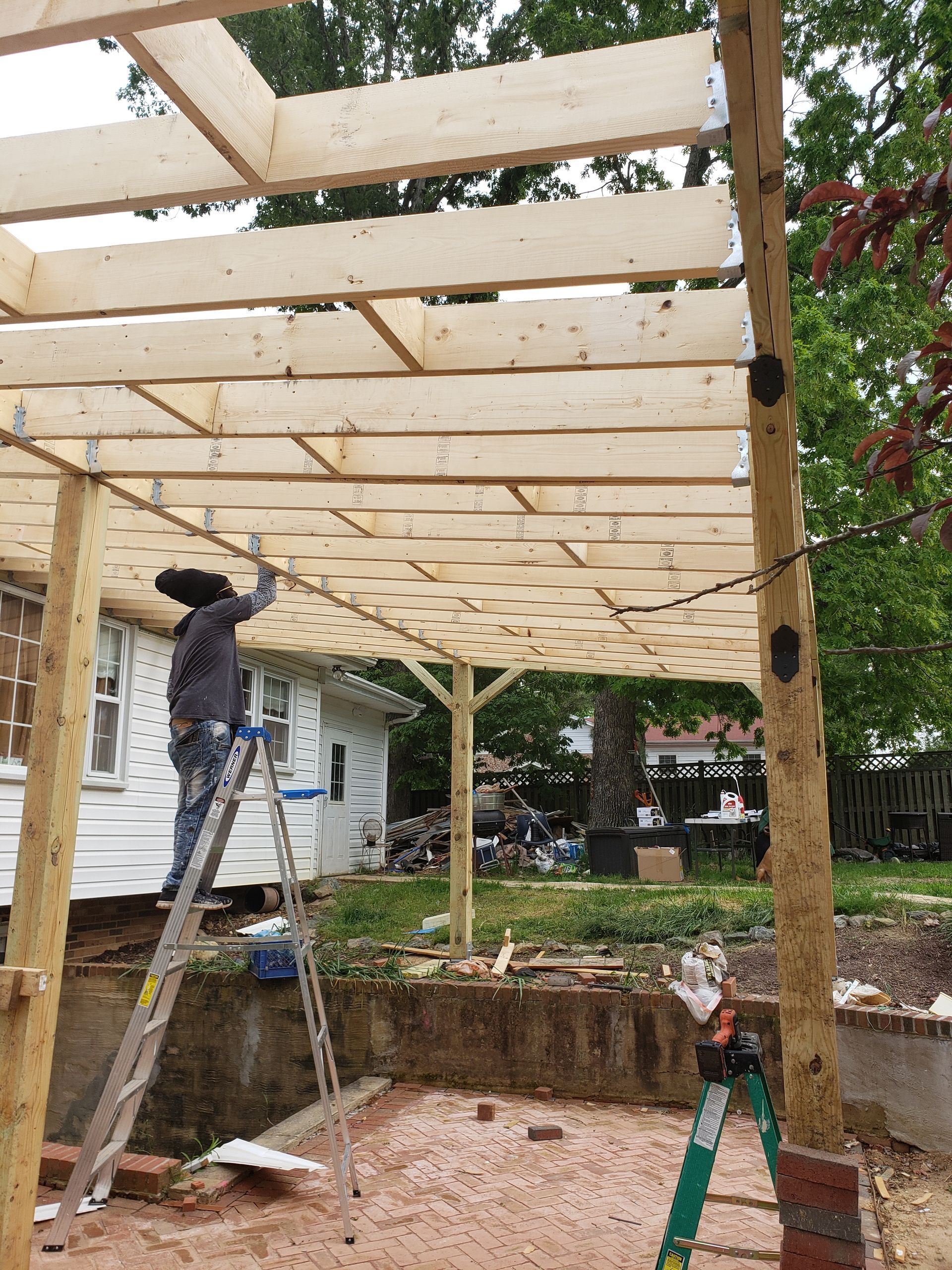Two-story house under construction with wooden frame and unfinished roof, set against a cloudy sky.