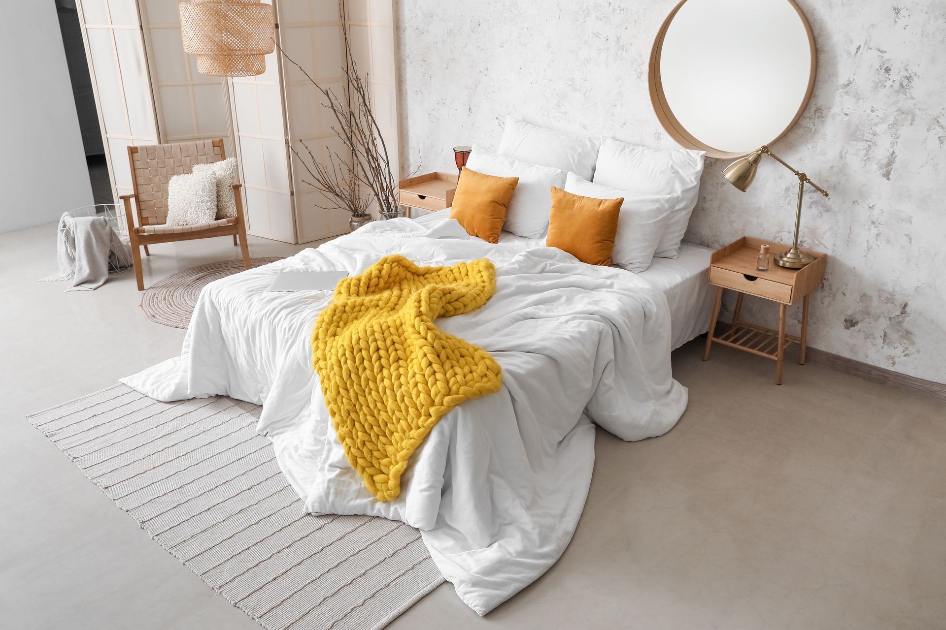 A bedroom with a bed , nightstand , chair and mirror.