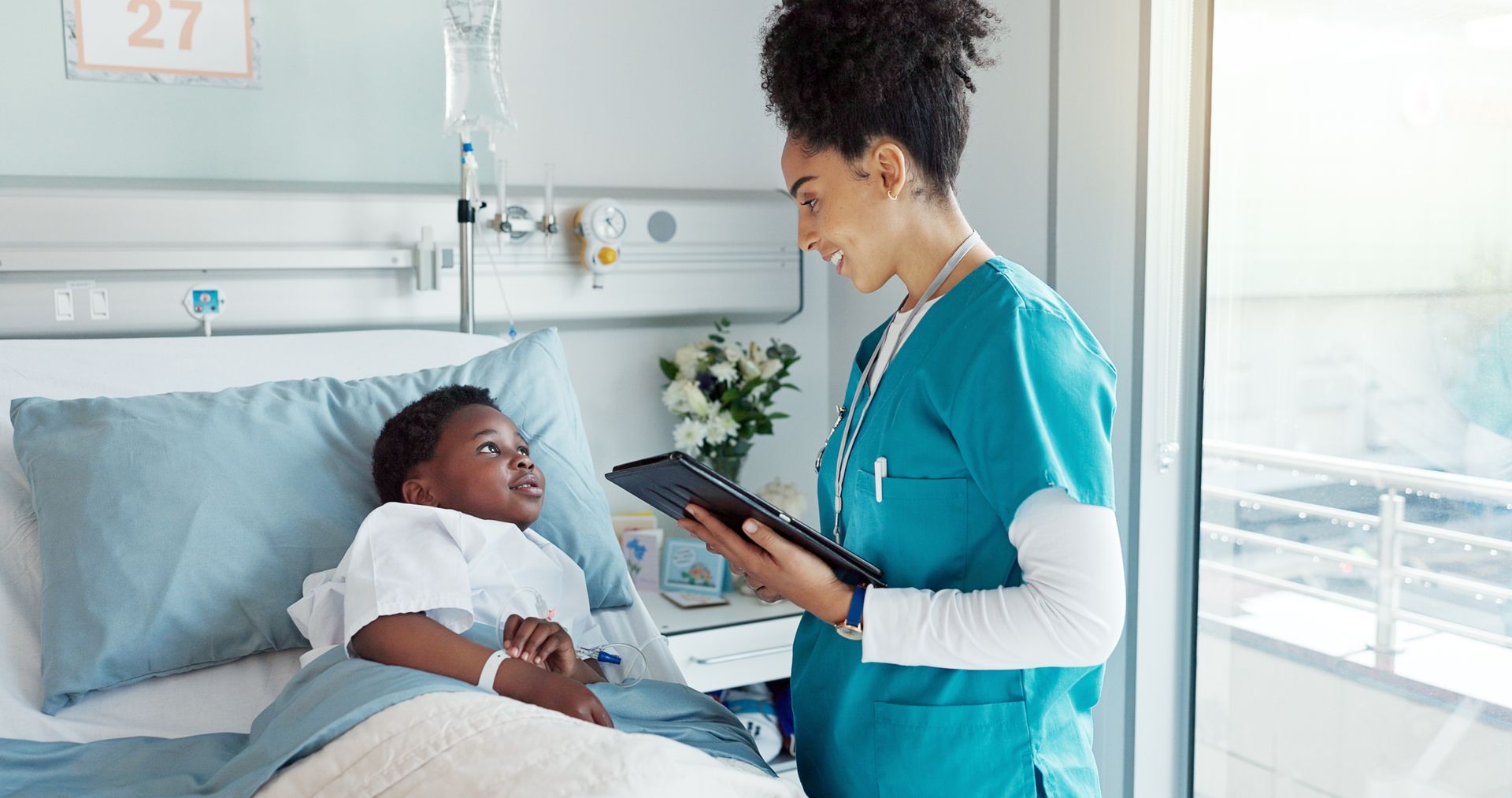 A nurse is talking to a child in a hospital bed.